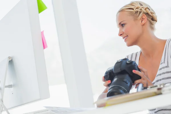 Attractive photo editor looking at a digital camera — Stock Photo, Image