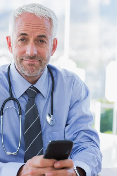 Attractive doctor using his smartphone — Stock Photo, Image