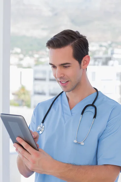 Mandlig sygeplejerske arbejder på en tablet pc - Stock-foto