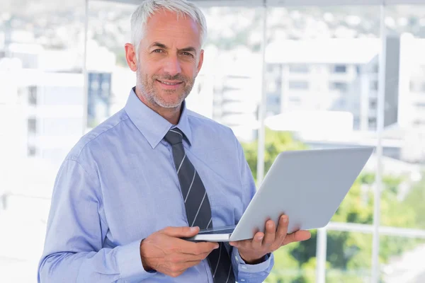 Sonriente hombre de negocios sosteniendo portátil — Foto de Stock