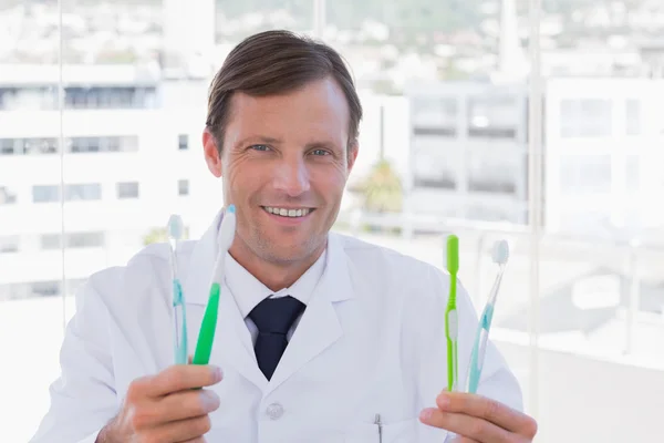 Feliz doctor sosteniendo dos cepillos de dientes — Foto de Stock