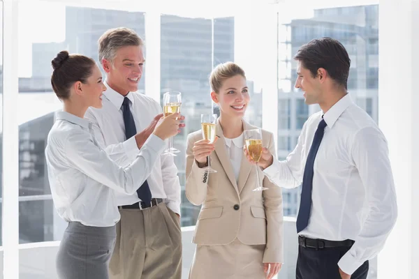Улыбающаяся команда бизнеса, звенящая флейтами шампанского — стоковое фото