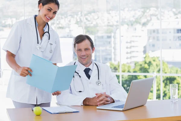 Ganska läkare visar en mapp till en kollega — Stockfoto