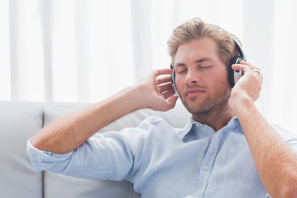 Hombre escuchando música en un sofá — Foto de Stock