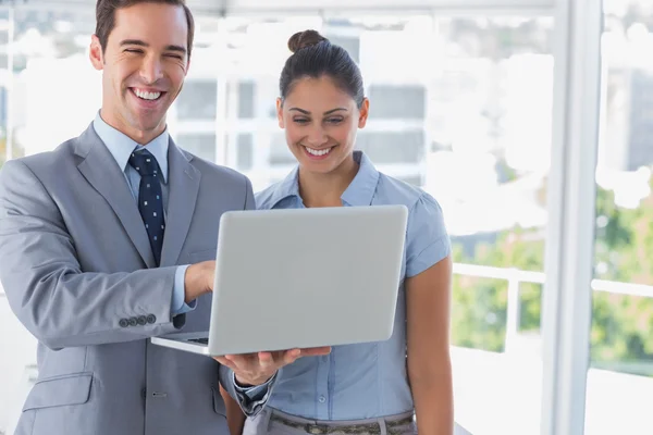 Compañeros de negocios mirando a la computadora portátil y riendo — Foto de Stock