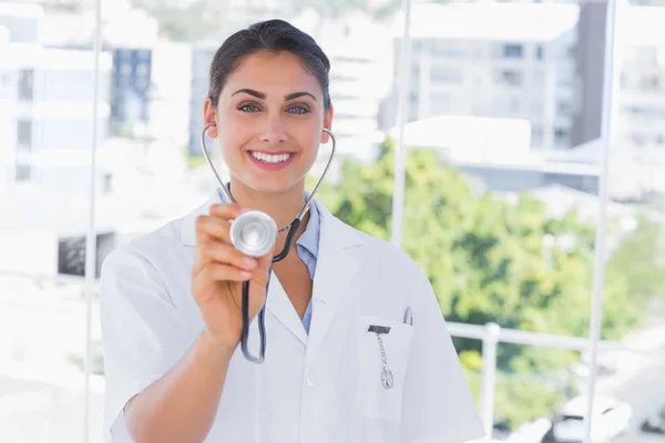 Leende ung läkare håller upp stetoskop — Stockfoto