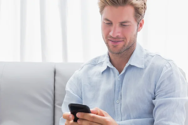 Homem usando seu telefone em um sofá — Fotografia de Stock