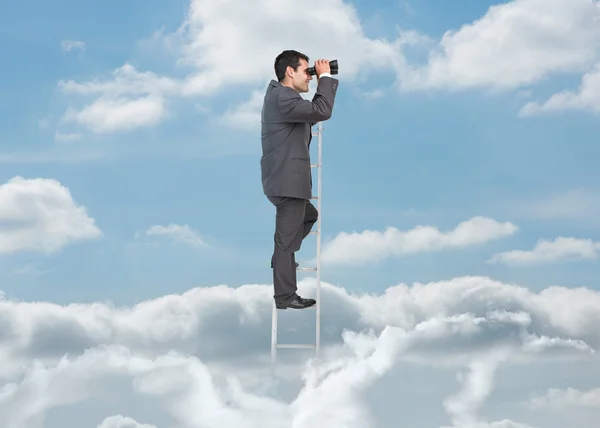 Businessman on ladder over the clouds — Stock Photo, Image