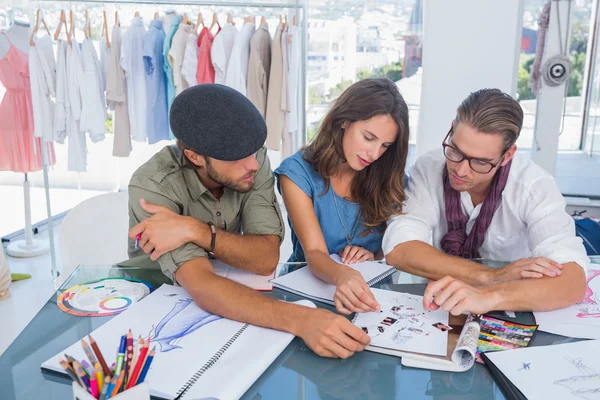 Três designers de moda trabalhando em um escritório brilhante — Fotografia de Stock