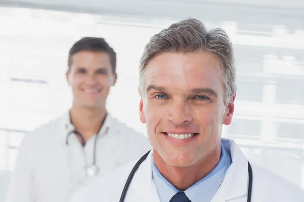 Médico sorridente em pé na frente de seu colega — Fotografia de Stock