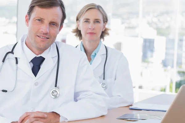 Group of doctors posing at their desk — Stock Photo, Image