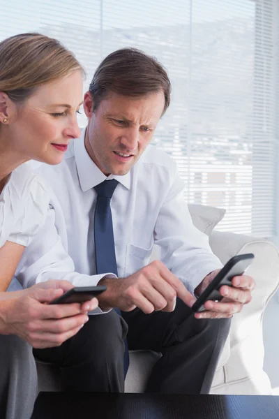 Lachende bedrijf met behulp van mobiele telefoons — Stockfoto