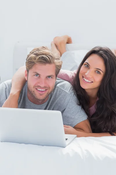 Mulher feliz abraçando marido enquanto usa um laptop — Fotografia de Stock