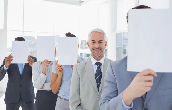 Verksamhet team som täcker ansiktet med vitboken utom en — Stockfoto