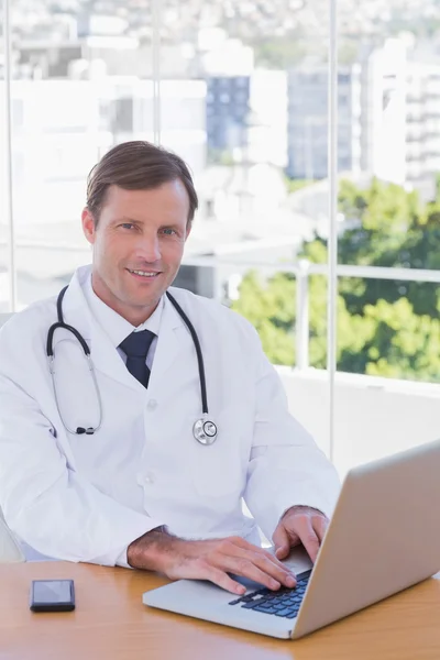 Usmívající se doktor pracuje na jeho laptopu — Stock fotografie