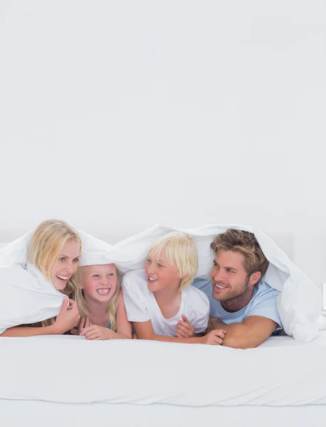 Cheerful family under the duvet — Stock Photo, Image