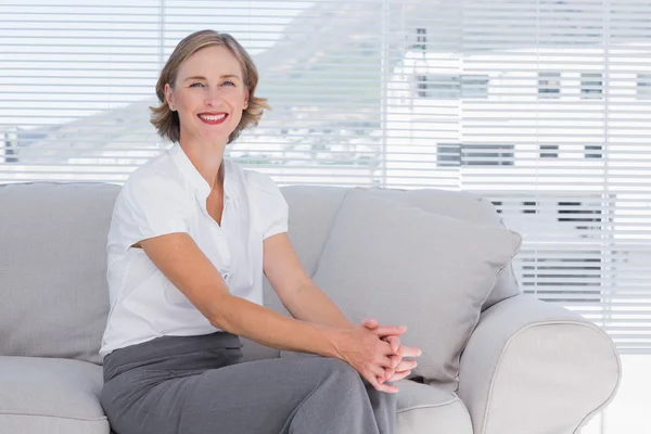 Mujer de negocios sonriente sentada en el sofá — Foto de Stock