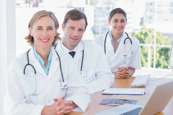 Médicos sonrientes posando en su escritorio —  Fotos de Stock