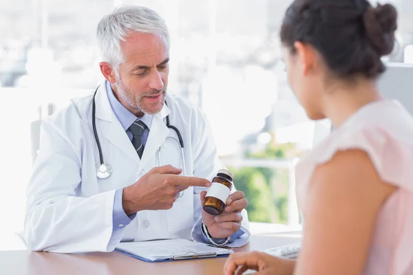 Doctor explicando el frasco de pastillas al paciente — Foto de Stock