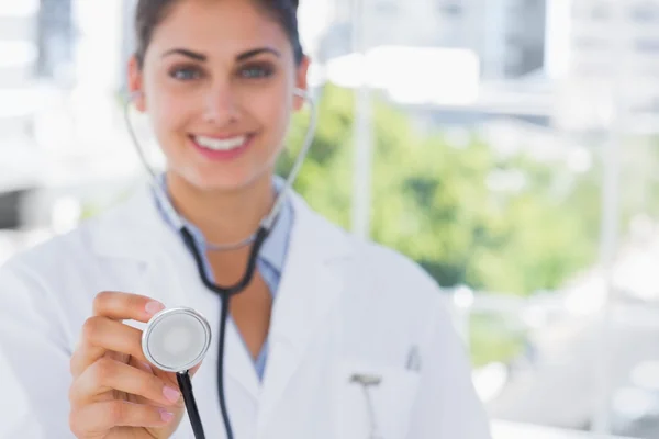 Pretty young doctor holding up stethoscope — Stock Photo, Image