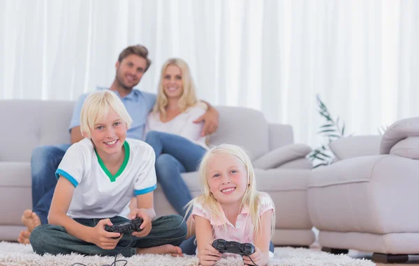 Дети, сидящие на ковре, играют в видеоигры — стоковое фото