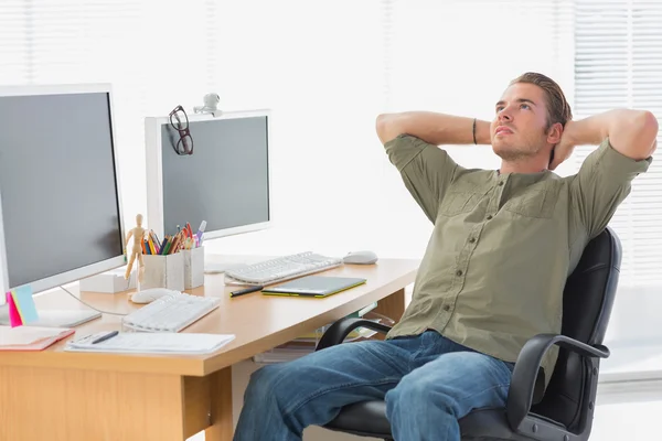 Bonito designer inclinado para trás em sua mesa — Fotografia de Stock