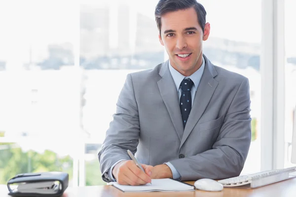 Lachende zakenman schrijven achter zijn Bureau — Stockfoto