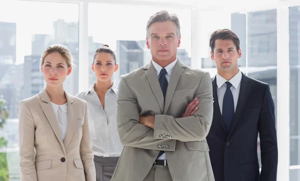 Босс со сложенными руками стоит рядом с серьезными коллегами. — стоковое фото