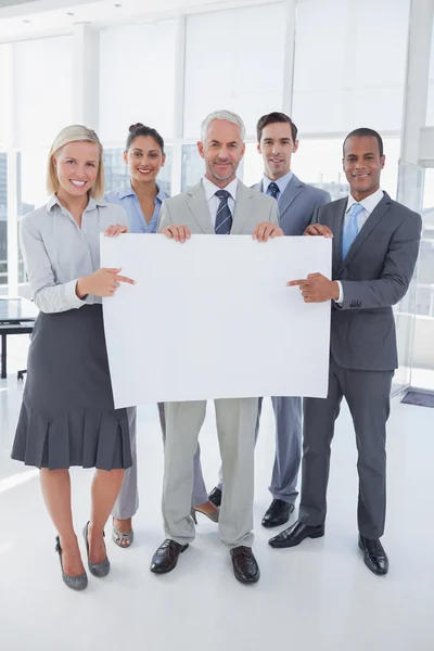 Business team holding large blank poster and smiling at camera — Stock Photo, Image