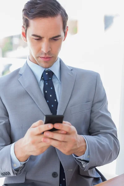 Серьезный бизнесмен пишет смс по телефону — стоковое фото