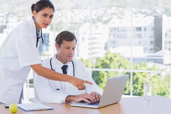 Médico apontando para o laptop de um colega — Fotografia de Stock