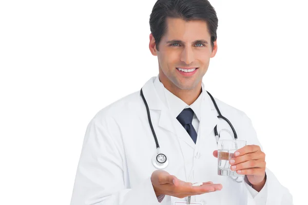 Happy doctor smiling and holding tablets and water — Stock Photo, Image