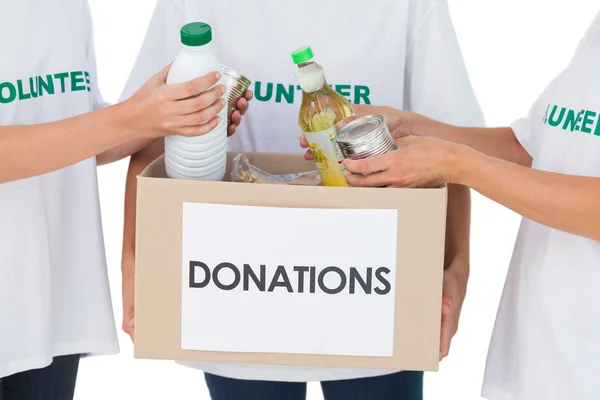 Группа волонтеров кладет еду в коробку для пожертвований — стоковое фото
