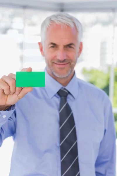 Lächelnder Geschäftsmann zeigt grüne Visitenkarte — Stockfoto