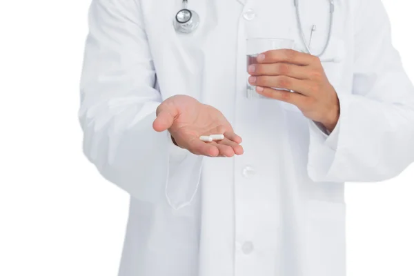 Doctor holding medicine and glass of water — Stock Photo, Image