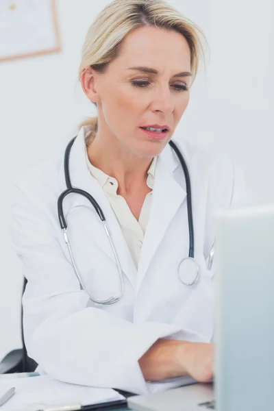 Portrait of a serious doctor working on her laptop — Stock Photo, Image