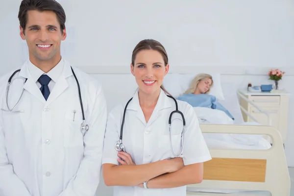 Two doctors standing in front of a hospitalized patient Royalty Free Stock Photos