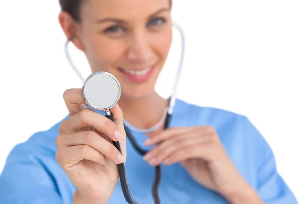 Smiling surgeon holding up stethoscope Stock Photo