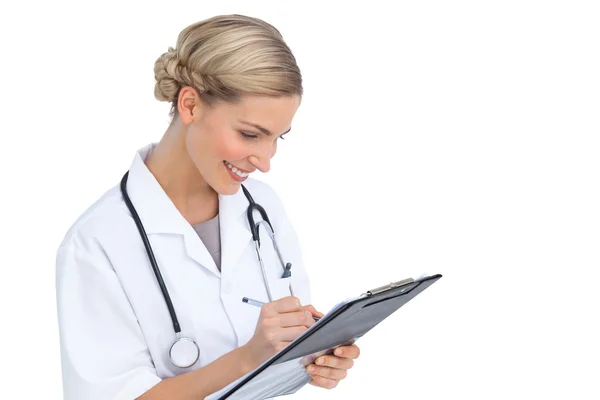 Улыбающаяся медсестра, пишущая на планшете Стоковое Изображение