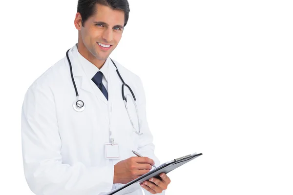 Doctor writing on his clipboard and smiling Royalty Free Stock Photos