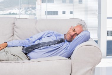 Businessman lying on sofa resting clipart