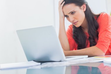 Confused designer looking at her laptop clipart