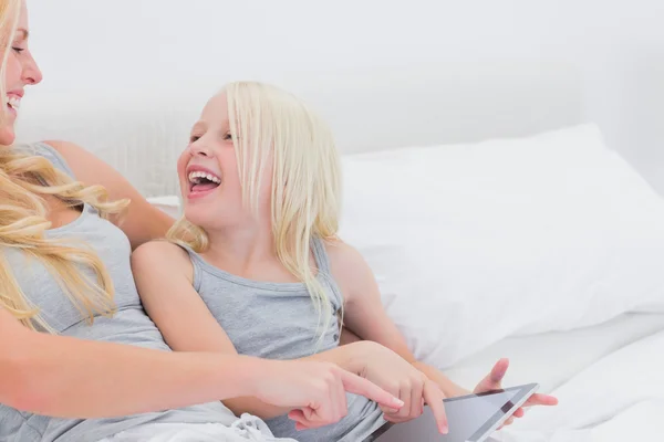 Madre e hija riendo mientras usan una tableta — Foto de Stock