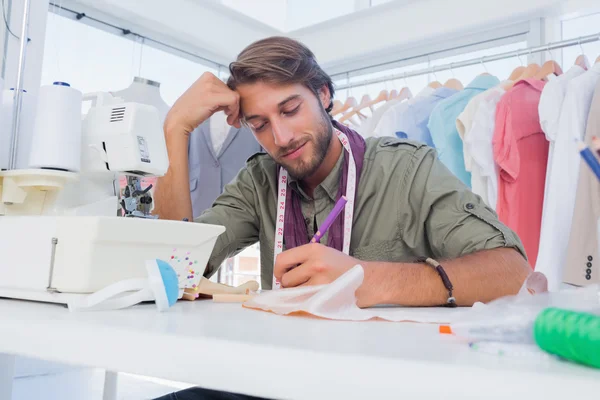 Sonriente diseñador de moda trabajando en su escritorio — Foto de Stock