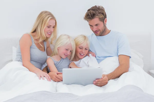Hermosa familia usando un portátil en la cama — Foto de Stock