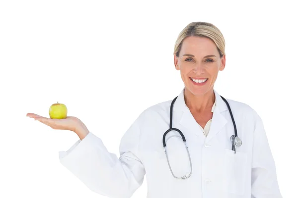 Happy doctor holding apple and looking at camera — Stock Photo, Image