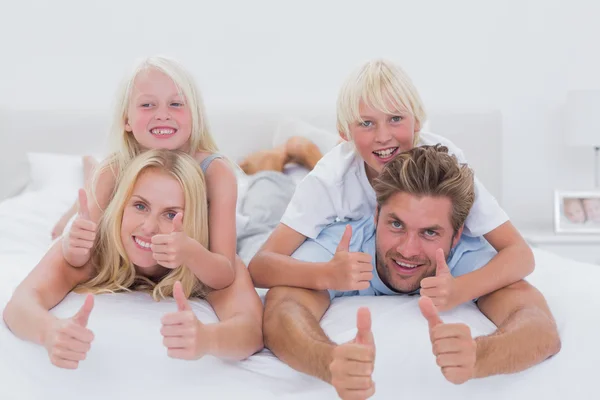 Parents giving piggy back to their children while giving thumbs — Stock Photo, Image
