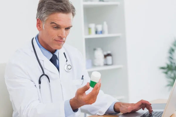 Médecin sérieux tenant une bouteille de pilules — Photo