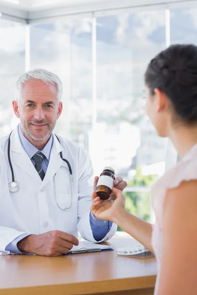 Пациент держит бутылку таблеток перед врачом — стоковое фото