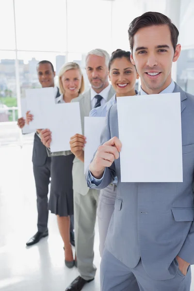 Business team in a line holding white pages — Stock Photo, Image